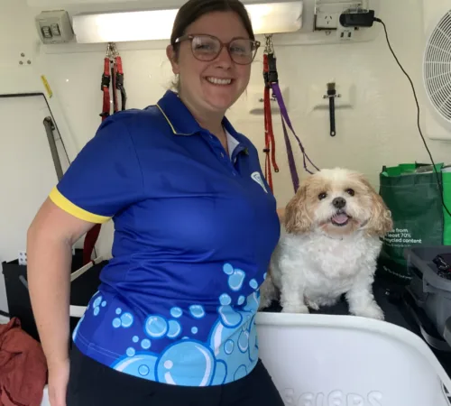Blue Wheelers dog groomer poses with a dog she just groomed